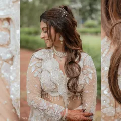 A detailed close-up of the bride, focusing on her soft smile and elegant hairstyle. The natural, leafy background complements her intricate white outfit perfectly.