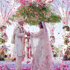 A shower of petals during the varmala ceremony, a moment of pure, uncontainable joy. Our goal is to freeze these energetic, happy moments in time, preserving the vibrant spirit of your celebration.