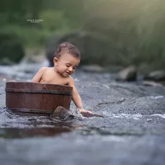 A true water baby! This little one loved splashing around during his outdoor photoshoot. We use props like this rustic wooden tub to add a special touch to our nature sessions.