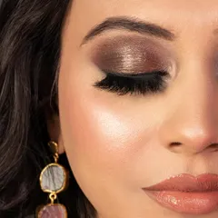 A close-up of a dark brown smokey eye with a pop of champagne shimmer on the lid. This technique adds dimension and brightness to the eye, creating a sophisticated and glamorous finish.
