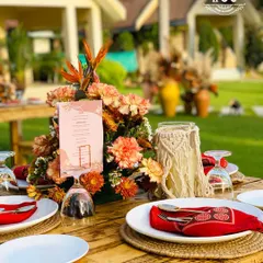 For a daytime event with a bohemian-chic theme, we created this beautiful tablescape using natural jute placemats, vibrant red napkins, and custom floral arrangements to complement the outdoor setting.