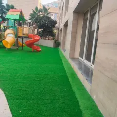 A side view of the same children's play area, showing how the artificial grass provides a clean, neat edge against the building's foundation.