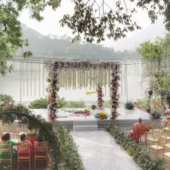 A serene lakeside mandap with delicate pink and white florals, offering a breathtaking natural backdrop for the ceremony.