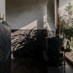 Natural light plays a huge role in our designs. In this powder room, the sunlight casts dramatic shadows of plants across the dark, textured tiles, creating a living piece of art.