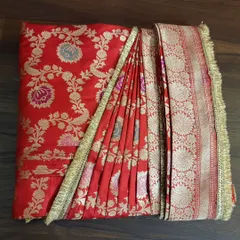 A top-down view of a box-folded red bridal saree. You can see how the pleats and the pallu are arranged to prevent wrinkles and make draping quick and easy.