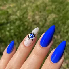 A close-up of the detailed evil eye nail art, featuring precise line work and tiny silver dot accents on a white base.
