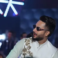 A candid shot of our client enjoying a wedding event in our custom Indowestern waistcoat. The off-white jacket features gold leaf-pattern embroidery, adding a touch of elegance to his look.