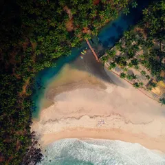 A top-down drone shot of a hidden beach in Goa, where a turquoise river meets the sea. This perspective reveals the stunning colors and natural composition of the coastline.
