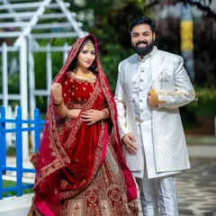 A classic combination featuring a bride in a grand red velvet lehenga and the groom in a sophisticated white sherwani. This pairing is timeless and ensures both partners look equally stunning in traditional pre-wedding photos.
