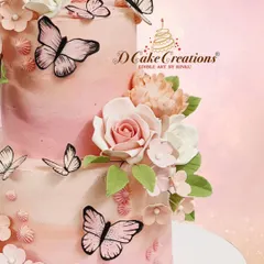 A close-up view of the butterfly and flower cake, showing the detail on the handcrafted sugar rose and the delicate, fluttering butterflies.
