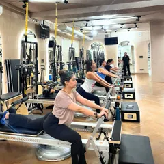 A full class of clients engaged in a rowing series on the Reformer. This exercise is fantastic for strengthening the back, shoulders, and core muscles.