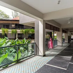 A wide corridor overlooking the club's courtyard, where patterned floor tiles and hanging plants create a pleasant, shaded walkway. These spaces, though not defined by a specific function, are vital to the project's atmosphere.