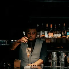 The subtle mastery behind the perfect drink. One of our talented bartenders is seen stirring a cocktail, a quiet moment of concentration that is essential to the craft.