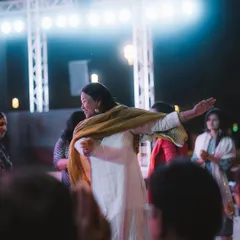 A woman dances with her arms outstretched, sharing a joyful moment with friends in the crowd. My focus is on capturing the natural interactions and happiness of the attendees.