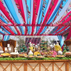 A vibrant fruit and cheese bar at a destination wedding in Bengaluru. The colorful canopy and rustic wooden counter create a festive, market-like feel, offering guests a fresh and interactive culinary experience.