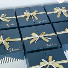 Elegant and uniform gift boxes for the entire groom's squad. These deep blue boxes are personalized with each groomsman's name in gold and tied with a beautiful ribbon.