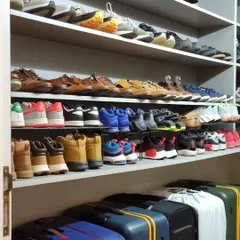 An organized shoe closet with footwear arranged by type. On the bottom shelf, you can see how we've stored luggage, making use of all the available space.