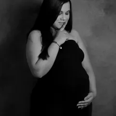 A stunning solo portrait in black and white. The simple background and classic lighting put all the focus on the mom-to-be's serene expression and the beautiful shape of her pregnancy.