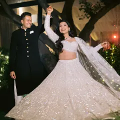 A candid moment of a couple lost in a dance. The bride's sparkling white lehenga twirls as they share a happy moment together during their sangeet celebration.