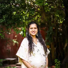 A classic solo maternity portrait that beautifully highlights the baby bump. The mother-to-be's warm smile and the lush green background create a serene and happy image, celebrating this special time in her life.