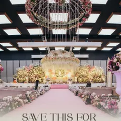 An indoor wedding setup designed for a fairytale. The aisle is lined with lush florals leading to a magnificent stage, all under a stunning floral chandelier, transforming the ballroom into a dreamscape for the pheras.