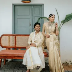 A classic portrait of Goutham and Aiswarya during their Hindu Brahmin wedding. Their coordinated outfits and joyful smiles are set against a backdrop of traditional decor.