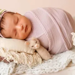 A perfect little bundle sleeping soundly. This photo showcases a full body wrap, which is ideal for keeping babies calm and posed beautifully in props like this tiny bed.