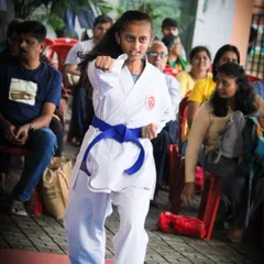 A young blue belt student executes a sharp, focused punch during a belt grading examination. This demonstrates the power and confidence that students build as they advance through the ranks.