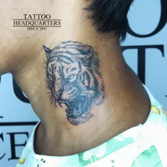 A fierce tiger head tattooed on the neck. The detailed line work and shading capture the animal's raw power and intensity.