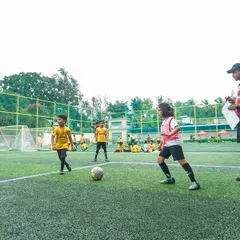 A coach observes a training match, clipboard in hand. We constantly assess player performance to provide targeted feedback and track progress throughout their development journey.