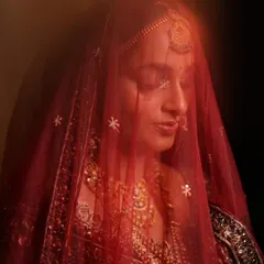 A dreamy, artistic shot of Laxmi through her red veil. This image perfectly captures the soft, ethereal quality of her traditional bridal makeup, highlighting a timeless and graceful aesthetic.