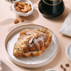 A bright and inviting shot of an almond croissant and coffee, perfect for a bakery's menu or social media. I styled this to create a perfect morning mood, highlighting the flaky pastry and fresh ingredients to attract customers.