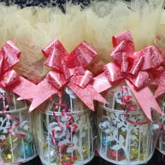 For a whimsical touch, I created these miniature birdcage favors filled with assorted chocolates. They are wrapped in netting and tied with a bright pink bow, making for a unique and memorable sweet treat.