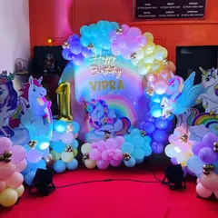 We created a magical unicorn wonderland for Vidra's first birthday. The setup glows with pastel rainbow balloons, sparkling unicorn cutouts, and a personalized neon sign, making it a truly enchanting celebration.