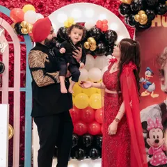 A beautiful family moment at a Mickey Mouse themed birthday party. The joy and love are so evident as they celebrate their son's special day together.