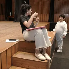 A one-on-one chat with a young actor on the steps of the stage. These quiet moments of mentorship are crucial for building trust and helping a child feel confident and prepared.