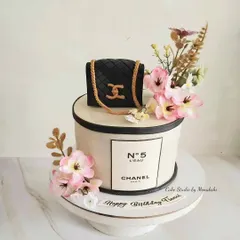 A chic Chanel themed cake for a fashion lover. This design features the iconic quilted bag and No. 5 perfume bottle, adorned with delicate flowers.