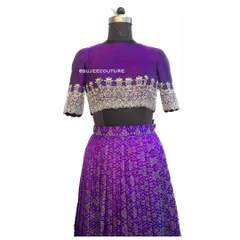 A studio shot of the purple Ikkat lehenga. The hand-embellished crop top blouse, with its intricate silver embroidery, is designed to perfectly complement the traditional weave of the lehenga skirt.