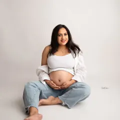 A happy and relaxed portrait. This mom-to-be's joyful smile is the centerpiece of this casual shot in jeans and a white top.