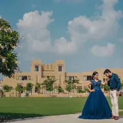 A classic romantic pose with the groom kissing his partner's hand, showcasing the full silhouette of the navy blue ball gown against a beautiful backdrop.
