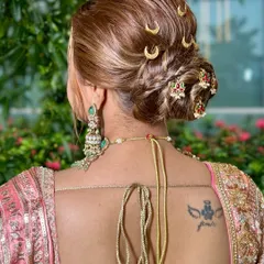 An elegant bridal bun for a modern Maharashtrian look, featuring intricate twists and traditional moon-shaped hairpins.