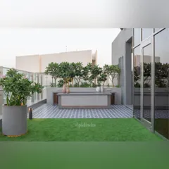 An outdoor bar and counter area on a rooftop terrace, set against a backdrop of trees that provide privacy and a green screen from neighboring buildings. The combination of a manicured lawn and elegant hardscaping makes it ideal for entertaining.