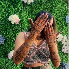 A happy bride showing off the dark, even stain of her full-arm mehndi.