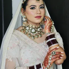 For this bride, we chose a contemporary yet timeless look with a stunning white lehenga. I focused on a dewy skin finish, soft pink eyeshadow with a hint of shimmer, and elegant Kundan jewelry to complete the Anand Karaj bridal style.