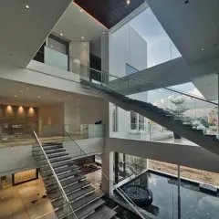 An orchestration of scale, light, and void. This double-height space features a magnificent floating staircase over a tranquil water body, where transparency becomes the soul of the home.