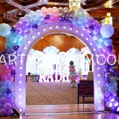 A grand entrance arch for a mermaid party, adorned with purple, blue, and silver balloons and lit from within to create a magical glow.
