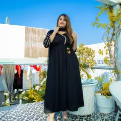 A full-length portrait on a sunny rooftop. The classic black anarkali stands out beautifully against the bright blue sky, creating a fresh and modern look for this ethnic wear shoot.