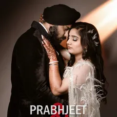 A warm, intimate studio portrait with soft lighting. The focus is on the couple's tender embrace and the intricate details of their outfits and henna, creating a timeless and romantic image.