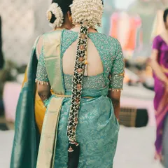 A detailed look at a traditional South Indian bridal hairstyle. This long braid is intricately decorated with gajra and golden accessories, a true statement piece for any bride.