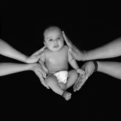 This artistic black and white photograph symbolizes the circle of love and protection surrounding a new baby. It's a powerful, conceptual shot that we create to represent the strength of family bonds.